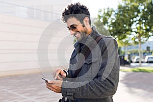 Modern young man using his mobile phone in the street.