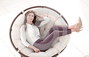 Modern young woman sitting in comfortable round chair