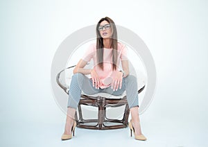 Modern young woman sitting in a round chair.