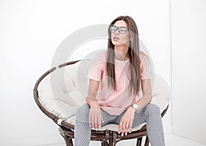 Modern young woman sitting in a round chair.