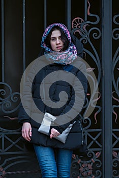 Modern young woman stands near a vintage iron gate