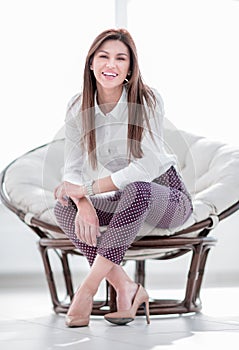 Modern young young woman sitting in a comfortable chair