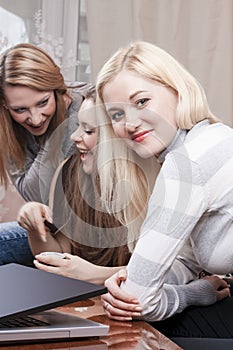 Modern Youth LIfestyle. Three Positive Winsome Caucaisan Girlfriends Having Fun While Working with Laptop Computer