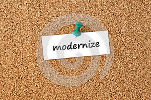 Modernize. Word written on a piece of paper, cork board background