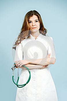 Modest cute young female doctor in a white robe over blue