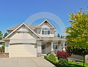Modest family house with concrete driveway to the garage on blue sky background