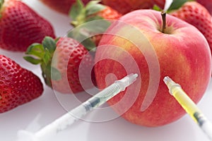 Modified food, fruits,apple and strawberries with punched needles and syringes