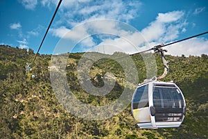 Modular cabins cable car against the bright sky, clouds ans mountains. Cableway - one of the popular urban rides in