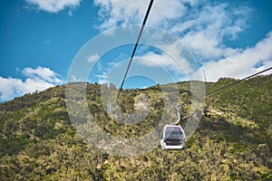 Modular cabins cable car against the bright sky, clouds ans mountains. Cableway - one of the popular urban rides in