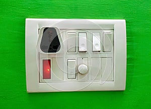 A Modular white electricity switch and socket board isolated on green wall