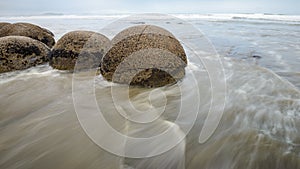 Moeraki boulders in the blurred Pacific Ocean waves