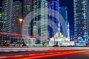 Mohammed Bin Ahmed Almulla mosque with buidings and light trails at night in Dubai