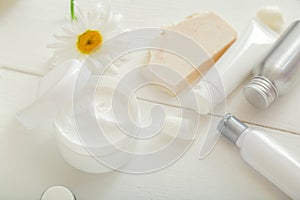 Moisturizer skin cream in white jar with chamomile flowers set white skincare products soap in tubes and bottles. Mockup white