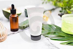 Moisturizing cream with a mockup on the background of a spa composition, tropical leaves, serum and gel.