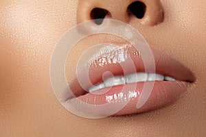 Moisturizing lip balm, lipstick. Close-up beautiful wet lips. Full lips with gloss lip makeup. Filler Injections