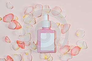 Moisturizing serum in a glass pink bottle with rose petals on a pink background with a shadow. Facial skin care product