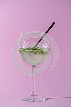 Mojito alcohol cocktail, tropical beverage with ice, mint and lime on pastel pink background with copy space