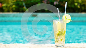 Mojito cocktail at the edge of a resort pool. Concept of luxury