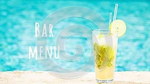 Mojito cocktail at the edge of a resort pool. Concept of luxury vacation. Bar menu wording