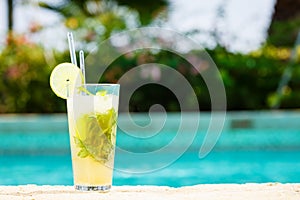 Mojito cocktail at the edge of a resort pool. Concept of luxury