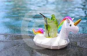 Mojito cocktail at the edge of a resort pool in inflatable unicorn. Concept of luxury vacation