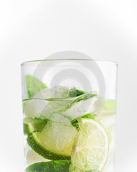 Mojito cocktail in a glass on a white background close-up cold light drink. Lime slices, mint leaves and ice cubes