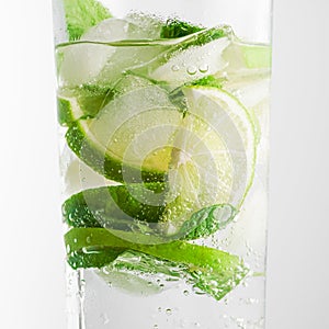 Mojito cocktail in a glass on a white background close-up cold light drink. Lime slices, mint leaves and ice cubes