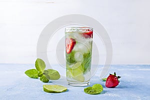Mojito cocktail with ice cubes. Glass of Summer lemonade or ice tea. Refreshing cool detox drink with strawberry, lime and mint on