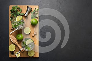 Mojito cocktail ingredients, lime, mint, water, jigger on black table. View from above. Horizontal format