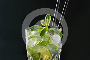 Mojito cocktail or lemonade with lime and mint in glass on black. Close up. Summer drink