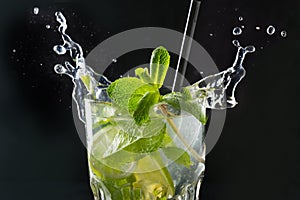 Mojito cocktail or lemonade with lime and mint in glass on black. Close up. Summer drink