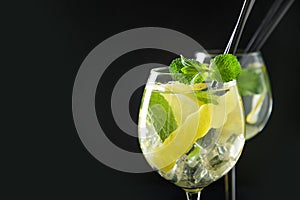 Mojito cocktail or lemonade with lime and mint in glass on black table. Close up. Summer drink