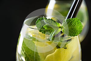Mojito cocktail or lemonade with lime and mint in glass on black table. Close up. Summer drink