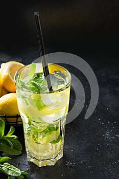 Mojito cocktail or lemonade with lime and mint in highball glass on black table. Close up. Summer drink