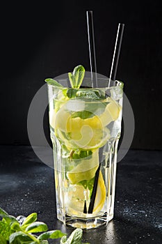 Mojito cocktail or lemonade with lime and mint in highball glass on black table. Close up. Summer drink