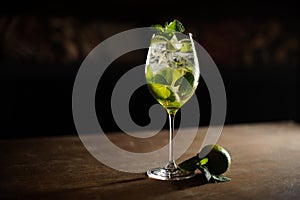 Mojito cocktail with lime and mint in highball glass on a dark stone background