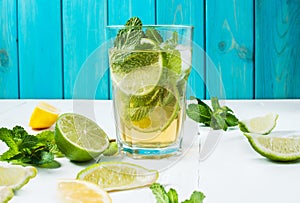 Mojito cocktail with lime and mint in highball glass on a wood table. Blue background