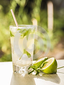 Mojito cocktail with lime, sugar, ice and mint leaves in the sunlight. photo