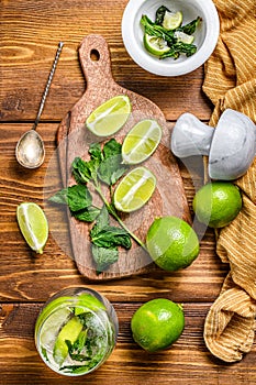 Mojito cocktail making. Ingredients Mint, lime, ice and bar utensils. Wooden background. Top view