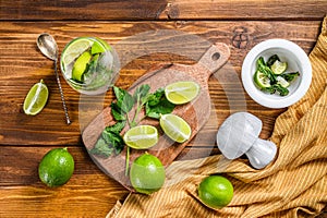 Mojito cocktail making. Ingredients Mint, lime, ice and bar utensils. Wooden background. Top view