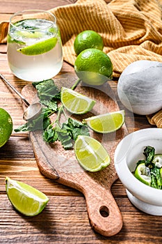 Mojito cocktail making. Ingredients Mint, lime, ice and bar utensils. Wooden background. Top view