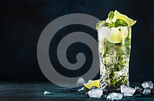 Mojito cocktail or mocktail with lime, mint, and ice in glass on blue background. Summer cold alcoholic non-alcoholic drink,