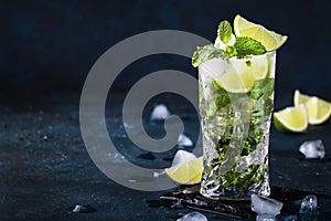 Mojito cocktail or mocktail with lime, mint, and ice in glass on blue background. Summer cold alcoholic non-alcoholic drink,