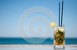 Mojito cocktail on a table in front of the beach with blue sky background photo