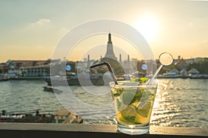 Mojito cocktail on table in rooftop bar with famous place background. Wat Arun ,Bangkok ,Thailand