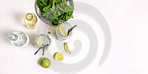 Mojito cocktail on a white background with copy space. Making a cold summer Mojito drink with lime, mint leaves, straw, ice cubes