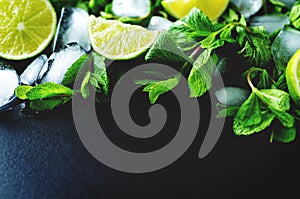 Mojito coctail ingredients with fresh mint leaves and lime slices on a black background