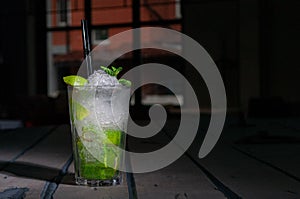 Mojito Long Drink decorated with lime and mint with crushed ice. In a glass goblet collins. On a gray wooden background. Close-up