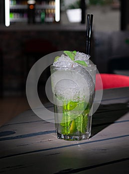 Mojito Long Drink decorated with lime and mint with crushed ice. In a glass goblet collins. On a gray wooden background. Close-up