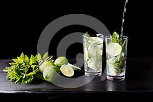 Mojito traditional beach refreshing cocktail alcohol drink in glass bar preparation pouring soda water, lime, mint